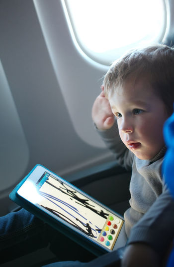 Close-up of boy with digital tablet in airplane