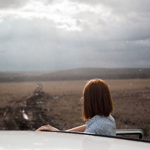Woman looking at view while standing by car