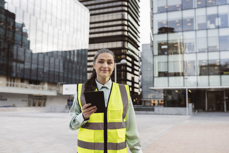 Female architect with tablet pc standing outside modern building