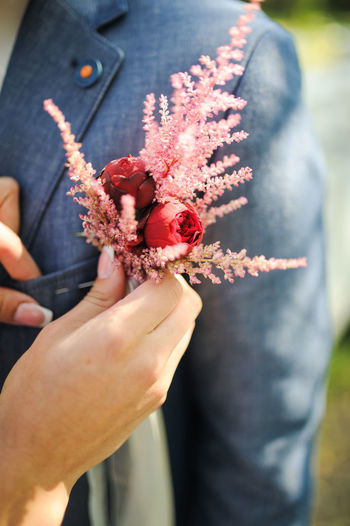 Cropped hands of woman putting roses in man pocket