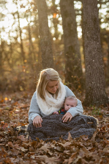 Woman with son sitting on field in forest