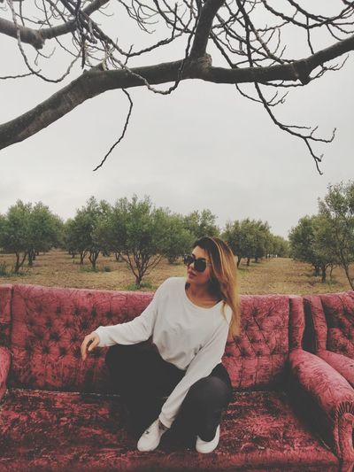 Young woman sitting on plant against sky