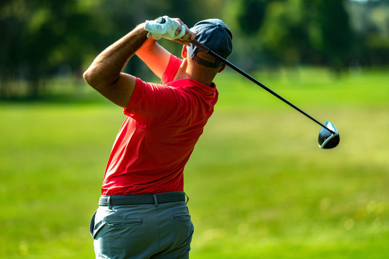 Professional golfer in a swing using a driver golf club, rear view