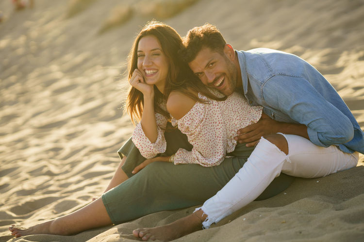 Laughing young couple sitting on beach