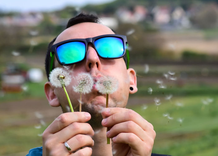 Portrait of man blowing dandelion