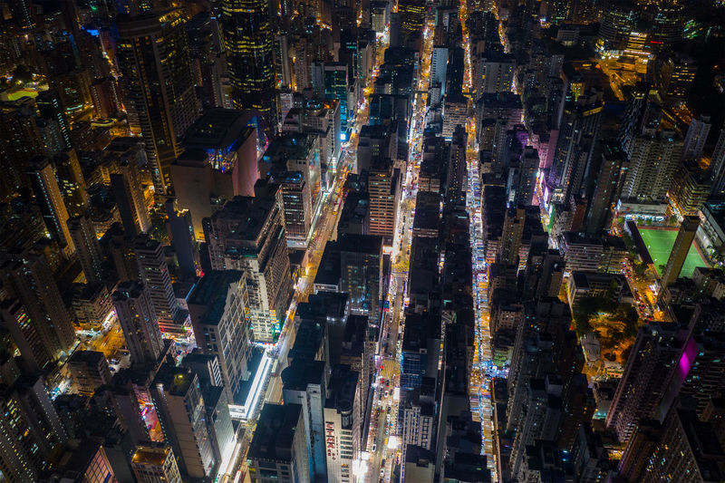 Aerial view of illuminated street amidst buildings in city at night