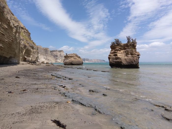Rock formation on beach against sky