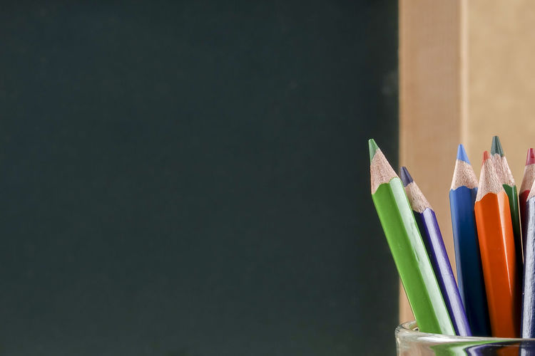Close-up of colorful pencils and blank writing slate