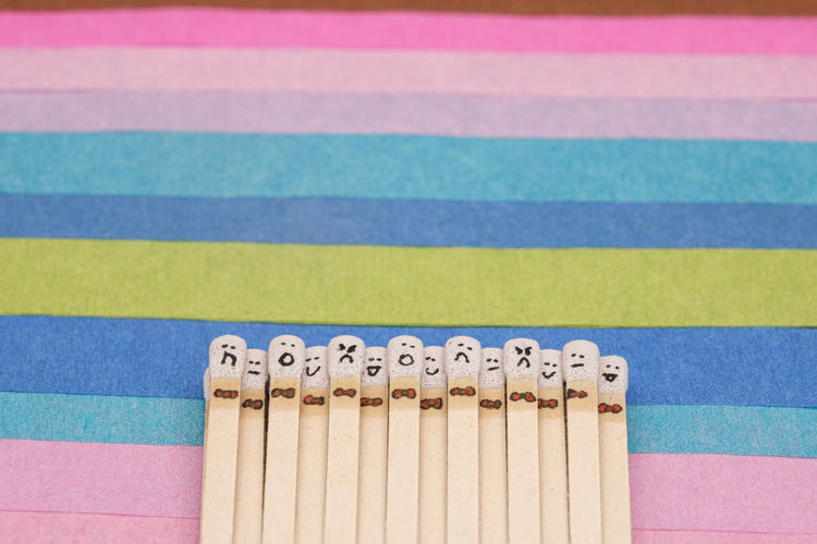 Matchsticks with faces painted on the heads on multicolored paper