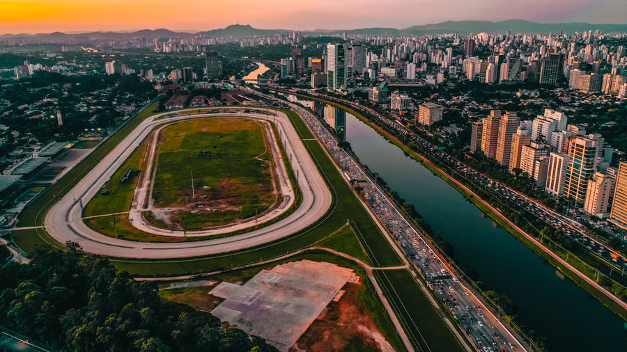 Aerial view of sports field in city against sky during sunset