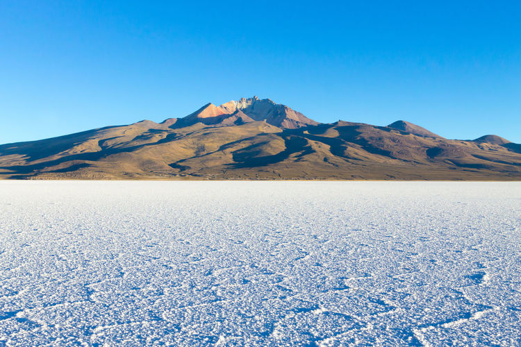 Scenic view of sea and mountains against clear blue sky