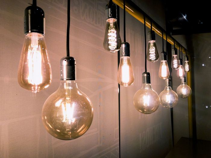 Illuminated light bulb hanging on wall