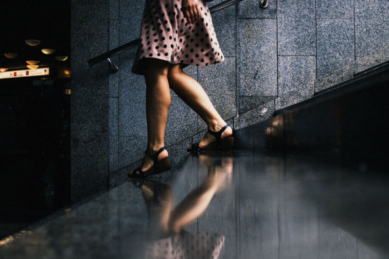 Low section of woman walking on steps by reflection