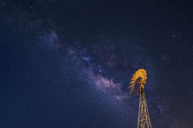 Low angle view of windmill against star field