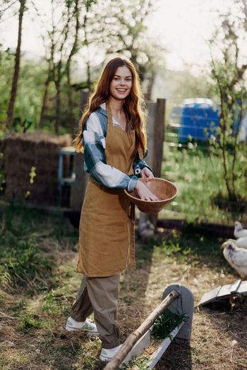 Happy female farmer feeding chickens at farm