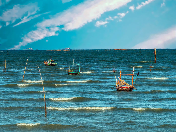 Fishing boats in sea against sky