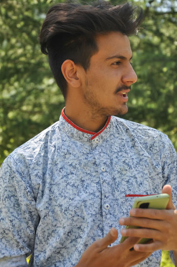 Young man looking away while using mobile phone