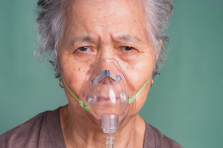 Close-up of an elderly asian woman wearing a medical breathing mask.