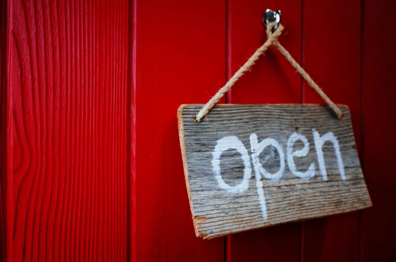 Close-up of open sign on wooden plank hanging to wall