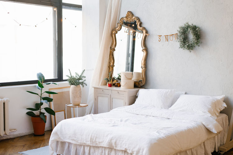 A double bed with white linens and pillows in the bedroom decorated for christmas and new year