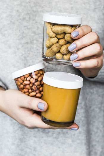Close-up of hand holding peanut jars