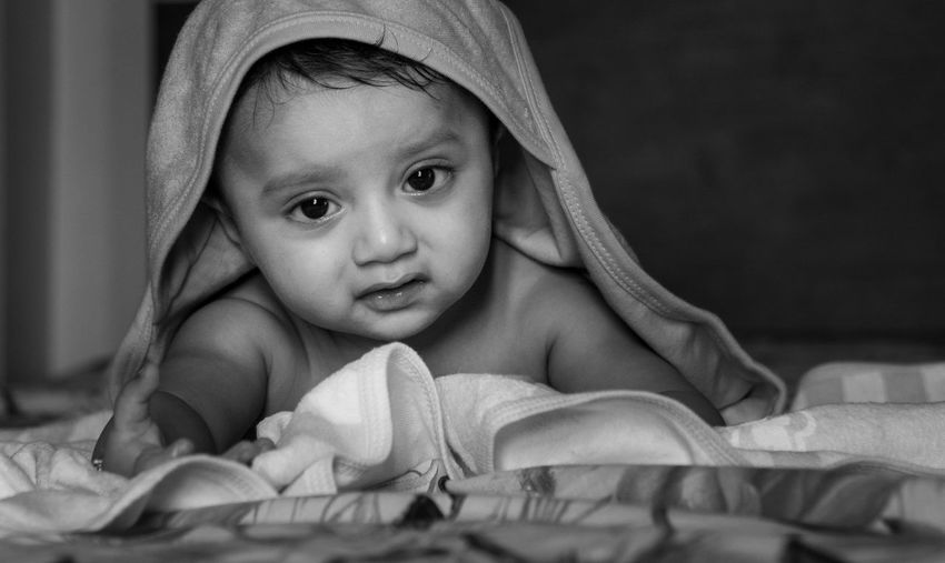 Portrait of cute baby wrapped in blanket at home 