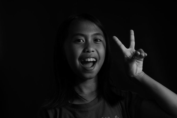 Portrait of smiling young woman against black background
