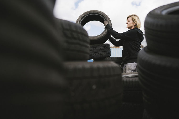 Female mechanic stacking car tires