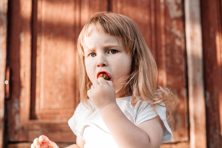 Portrait of cute girl eating strawberry