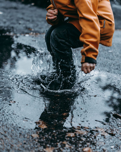 Low section of man jumping on puddle