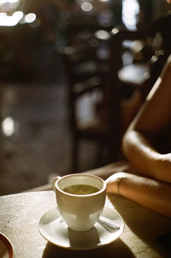 Cropped hand of woman sitting at restaurant with green tea on table