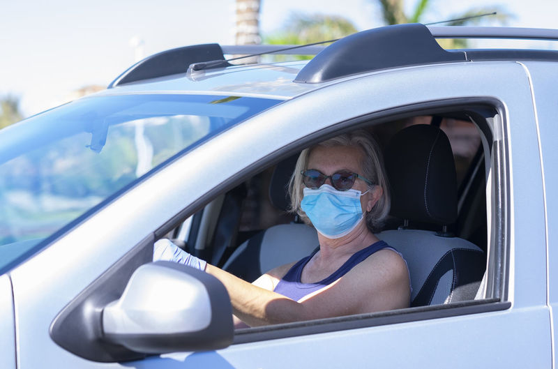 Portrait of senior woman wearing mask woman sitting in car