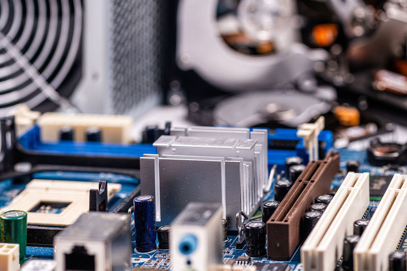 Fragment of computer circuit board with components on the background of defocused power supply fans
