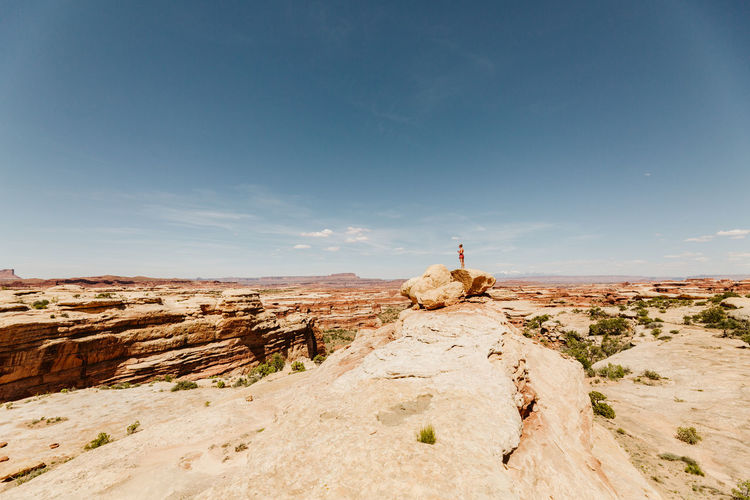 Female hiker stands atop rock overlooking red rock canyon in utah