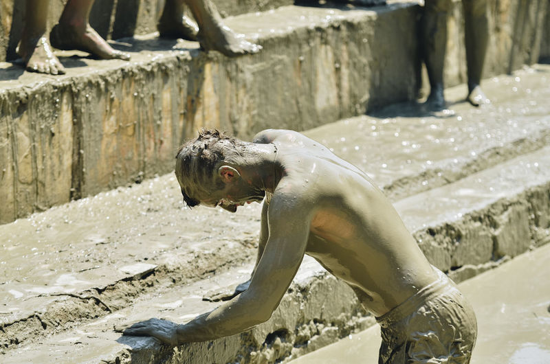 Side view of man covered in mud during traditional event