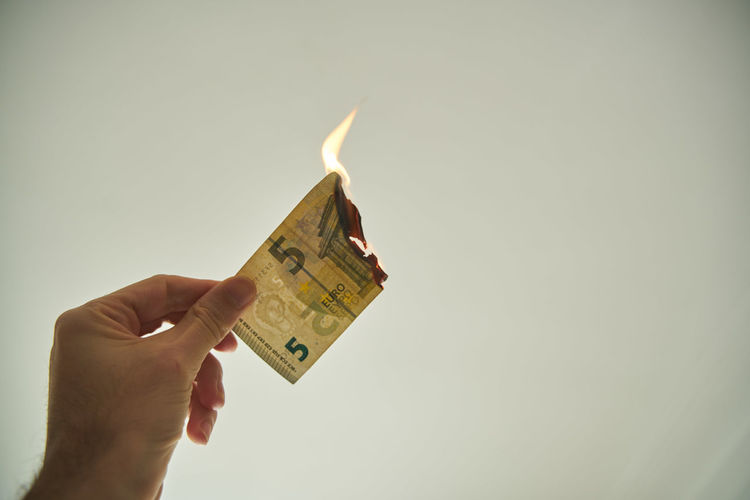 Low angle view of hand holding paper against gray background