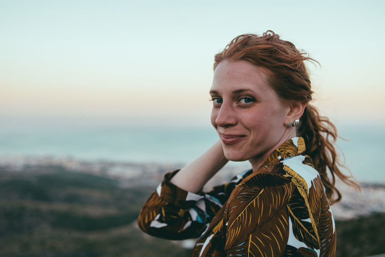 Portrait of smiling young woman against sky during sunset