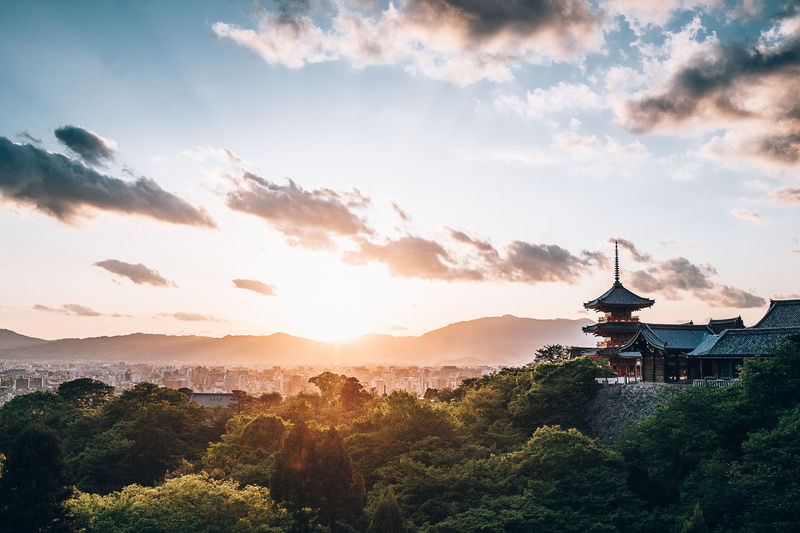 Scenic view of trees and buildings against sky during sunset