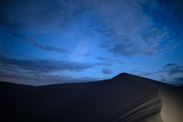 Low angle view of silhouette mountain against sky at night
