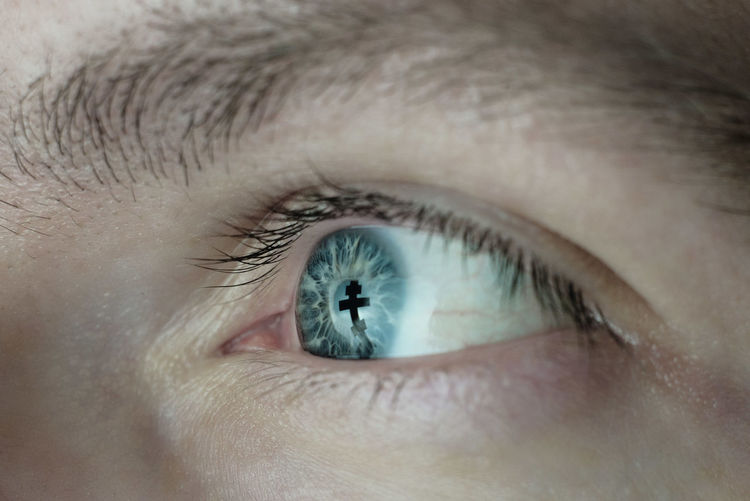 Close-up of man with reflection of cross in eye