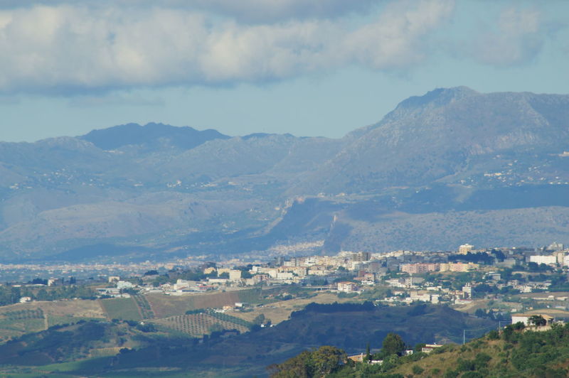 Aerial view of townscape and mountains against sky
