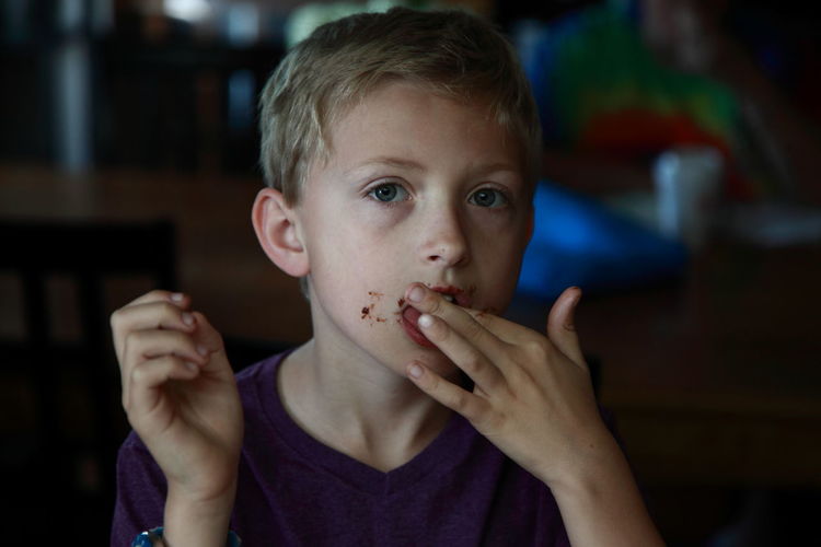 Close-up of boy licking chocolate off fingers