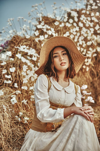 Portrait of girl wearing hat sitting against plants