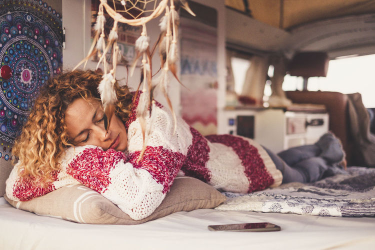 Young woman sleeping on bed in caravan
