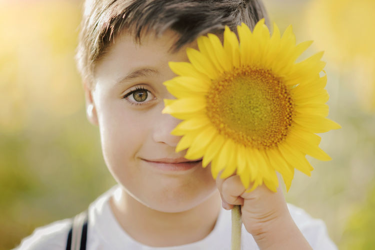 Close-up portrait of boy holding yellow flower