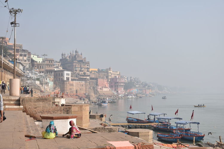 Boats in ganges by city against clear sky