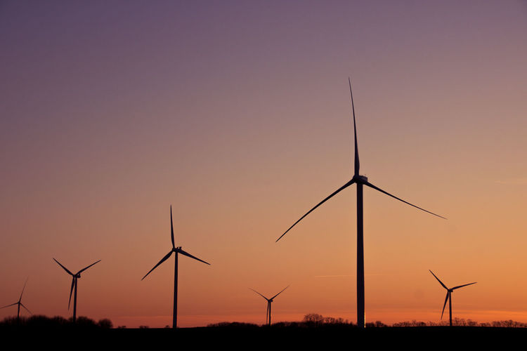 Low angle view of windmills against sky during sunset