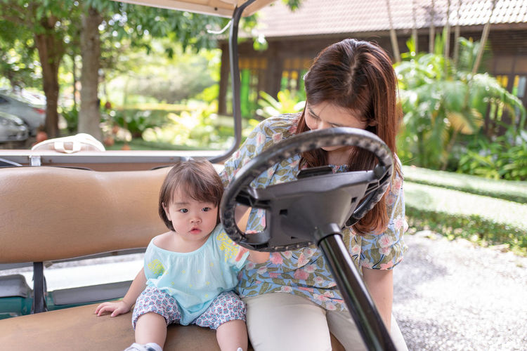 Woman sitting with daughter on golf cart