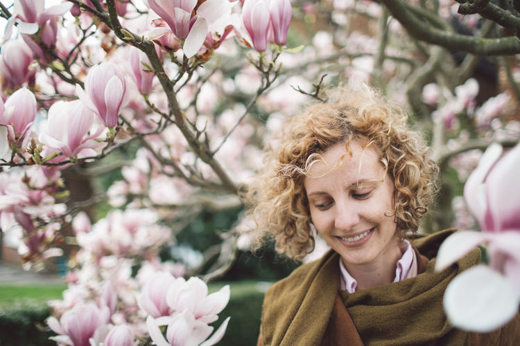 Smiling woman by flowers on branches