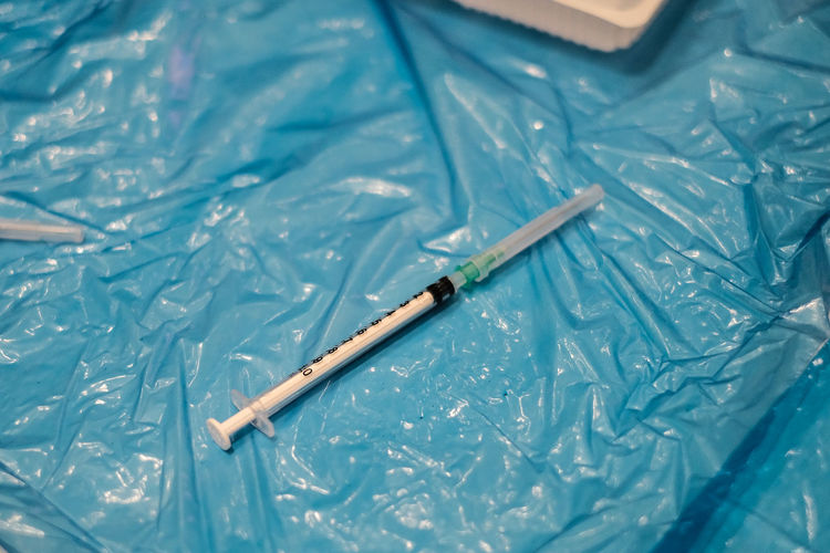 High angle view of a syringe on blue plastic sheet